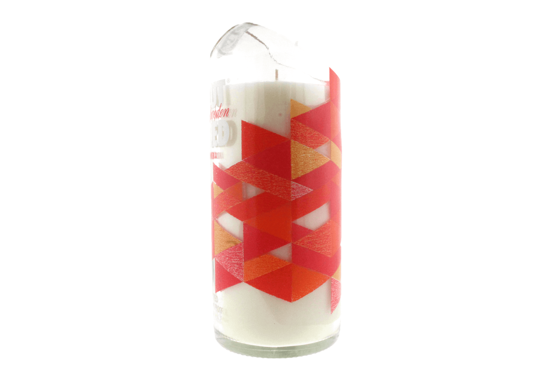 The Recycled Vodka Candle – Absolut Red Ruby is a hand-poured white soy candle in a clear glass container with a chipped rim and a geometric red and orange triangular pattern.