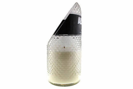 The Recycled Vodka Candle – Absolut is a white, all-natural soy candle hand-poured into a clear, textured glass container with an angled top and black label, adding a unique touch to any space.