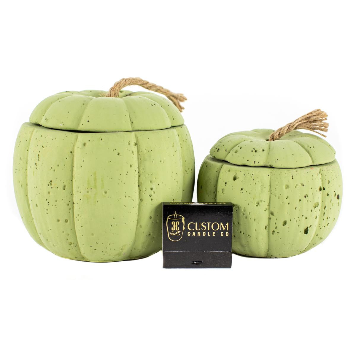 Two Green Cement Candles, each pumpkin-shaped with rope handles, are shown beside a black "Custom Candle Co." box on a white background.
