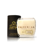 A Recycled Barcelo Imperial Dominican Rum Candle in a clear glass with a “Barceló Imperial” label sits next to a black cylindrical “Custom Candle Co.” box.