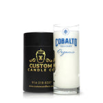 A Recycled Cobalto Tequila Blanco Candle sits next to its black Custom Candle Co. container, featuring their signature candle hand-poured into a repurposed tequila bottle.