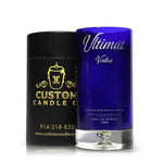 A Recycled Ultimat Vodka Candle in a blue bottle sits beside a black Custom Candle Co. container featuring gold text and logo.