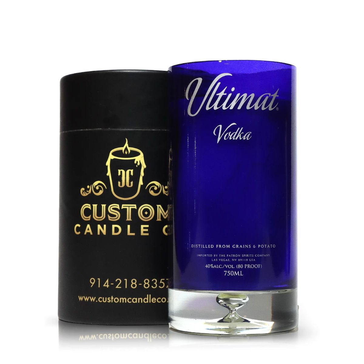 A Recycled Ultimat Vodka Candle in a blue bottle sits beside a black Custom Candle Co. container featuring gold text and logo.