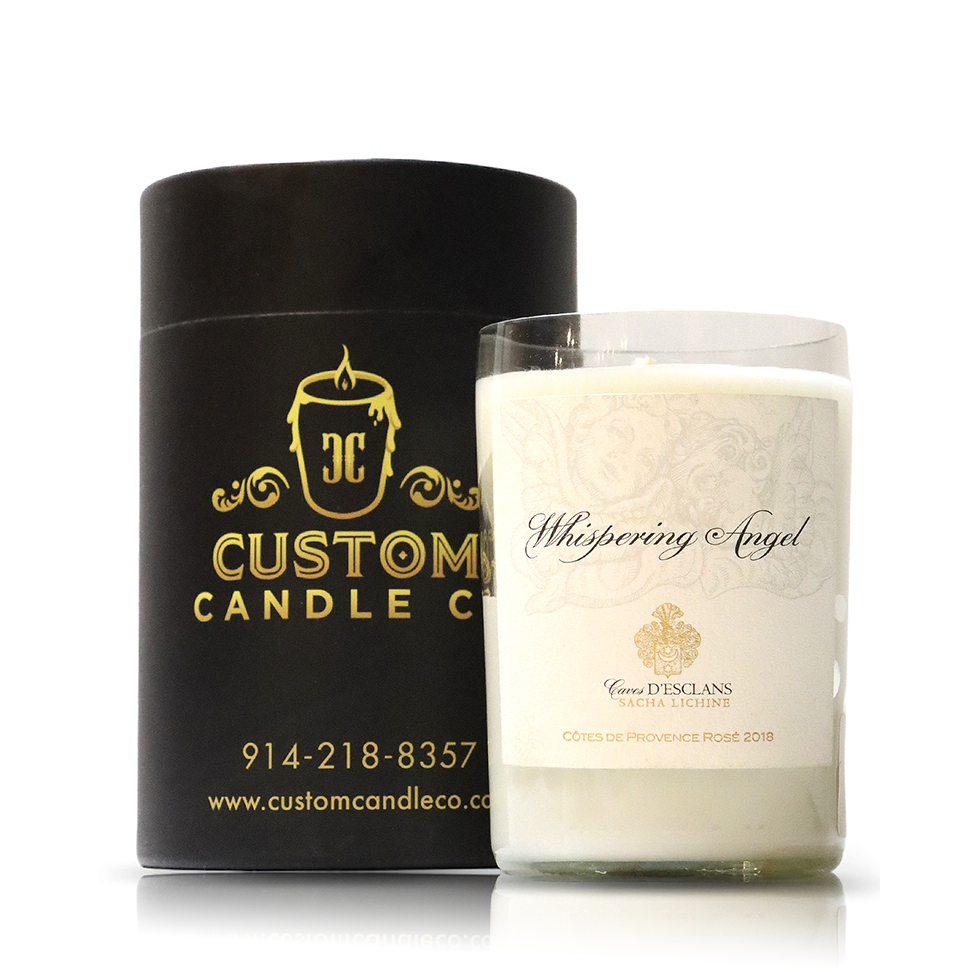 A white Recycled Whispering Angel Rose Wine Candle, crafted from upcycled materials, sits next to a black cylindrical box with gold Custom Candle Co. branding and contact information.