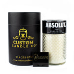 The Recycled Vodka Candle – Absolut is a hand-poured soy candle in a repurposed Absolut vodka glass, packaged in a black cylindrical box with a business card displayed in front.