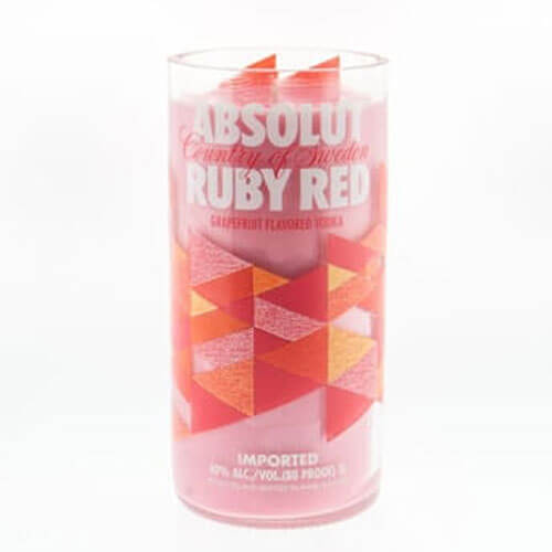 A clear glass holds a pink drink with geometric red and orange patterns and "Absolut Ruby Red" text, inspiring the Recycled Vodka Candle – Absolut Red Ruby, perfect for a custom or hand-poured soy vodka candle design.