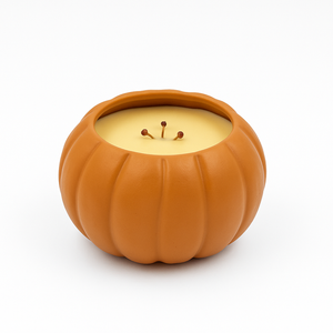 The Orange Ceramic Pumpkin Candle features three wicks and yellow soy wax in a reusable ceramic vessel, adding charm to any décor. Photographed on a white background.