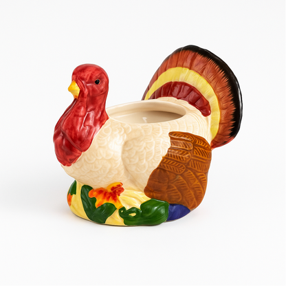 The Turkey Candle, a ceramic candle with colorful tail feathers and a hollow center, brings festive charm to your Thanksgiving décor, shown against a white background.