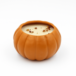 The Orange Ceramic Pumpkin Candle features a lit soy candle topped with decorative spices in a reusable ceramic pumpkin holder, set against a white background.