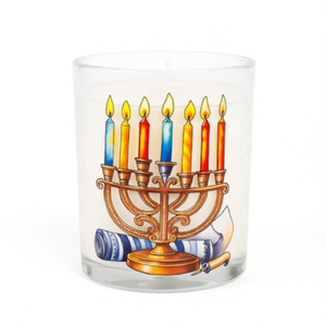 The Menorah Candle is a glass holder featuring a lit Menorah and scroll illustration, perfect as hand-poured Hanukkah décor.