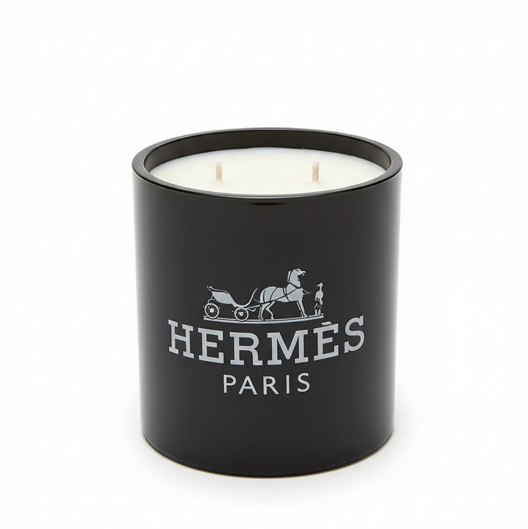 The Designer Paris Candle is a black, double-wick candle made from coconut-apricot wax, featuring the Hermès logo and white horse-drawn carriage design on the front—a true statement of luxury.