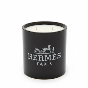 The Designer Paris Candle is a black, double-wick candle made from coconut-apricot wax, featuring the Hermès logo and white horse-drawn carriage design on the front—a true statement of luxury.