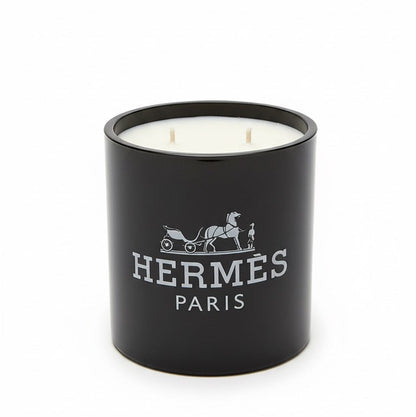 The Designer Paris Candle is a black, double-wick candle made from coconut-apricot wax, featuring the Hermès logo and white horse-drawn carriage design on the front—a true statement of luxury.
