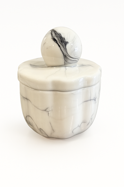 The Marble Luxe Candle features a round, white marble-patterned ceramic container with a matching lid and spherical handle, bringing luxury and elegance to any space. Set against a plain white background.