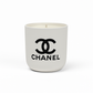 The Designer Ceramic Candle is a white soy candle in a ceramic cup featuring the black Chanel logo and brand name on the front, displayed against a plain white background.