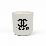 The Designer Ceramic Candle is a white soy candle in a ceramic cup featuring the black Chanel logo and brand name on the front, displayed against a plain white background.