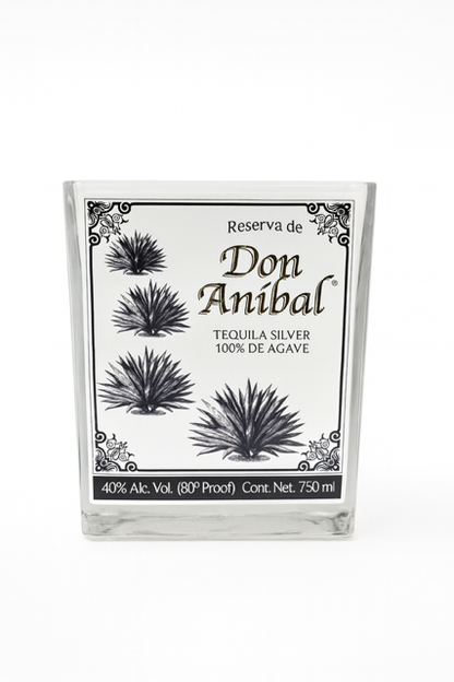 The Don Anibal Tequila Candle is upcycled from a 750ml Don Anibal Tequila Silver bottle with a white label, black agave art, and 40% Alc. Vol., made using natural soy wax for an eco-friendly touch.