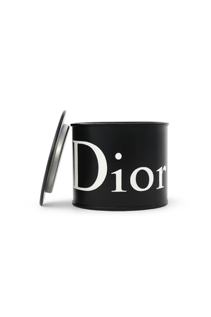 The Designer Black Paint Can Candle is a black, cylindrical candle with a partially open lid and "Dior" in large white letters, hand poured from soy for a luxurious, stylish touch to any space.