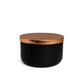 The Designer Noir Candle features a round black container with a metallic copper lid, adding sophistication to any space. Shown here against a plain white background.