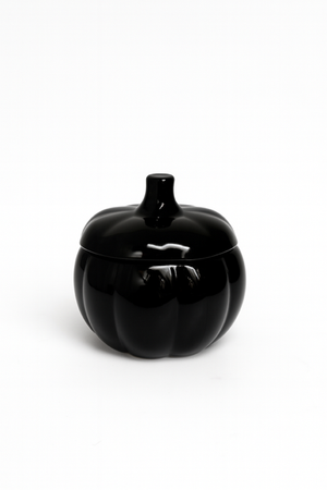 The Midnight Pumpkin Candle features a glossy black ceramic pumpkin-shaped container with a lid. Hand-poured with soy wax, it’s an elegant fall accent perfect for seasonal décor. Shown against a plain white background.