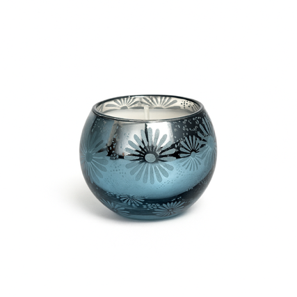 The Metallic Snowburst Candle features a blue glass holder with a floral metallic interior and round shape, making it perfect for holiday decor. Displayed on a white background for an elegant touch.
