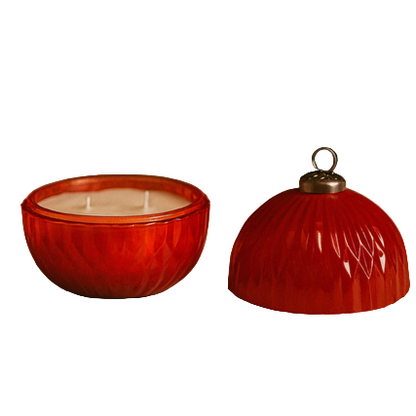The Red Ornament Candle is a round, refillable red candle holder with a matching lid featuring a metal loop, making it perfect as a Christmas ornament.