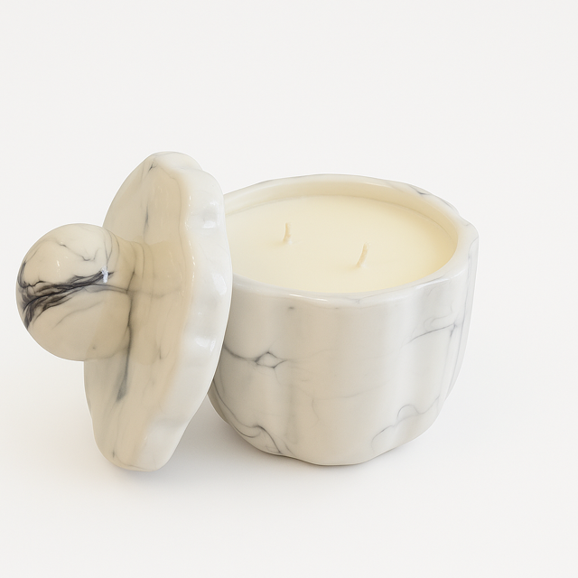 The Marble Luxe Candle features a white marble-patterned jar with two wicks and a matching lid placed beside it, all set against a white background.