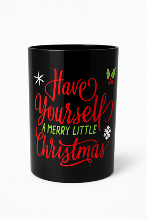 The "Have Yourself A Merry Little Christmas" 3 Wick Candle features a festive black mug with red and green script, snowflake accents, and a holly graphic—perfect for holiday decor.