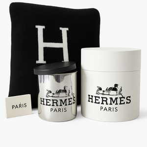 The Designer Paris Gift Set features a black Hermes cushion with an “H,” a metallic candle with black lid, a white box, and a “Paris” card—an elegant combination that pairs beautifully with a cotton throw for sophisticated home decor.