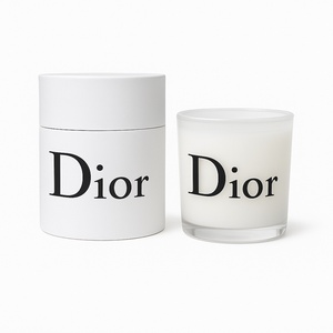 A white cylindrical Designer Glass Candle and its matching box are displayed side by side against a white background, highlighting the elegant, reusable candle jar.