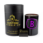 A black Recycled Champagne Candle – Luc Belaire Rose Fantome, featuring a purple "B," and a sleek black matchbox are displayed on a white background.