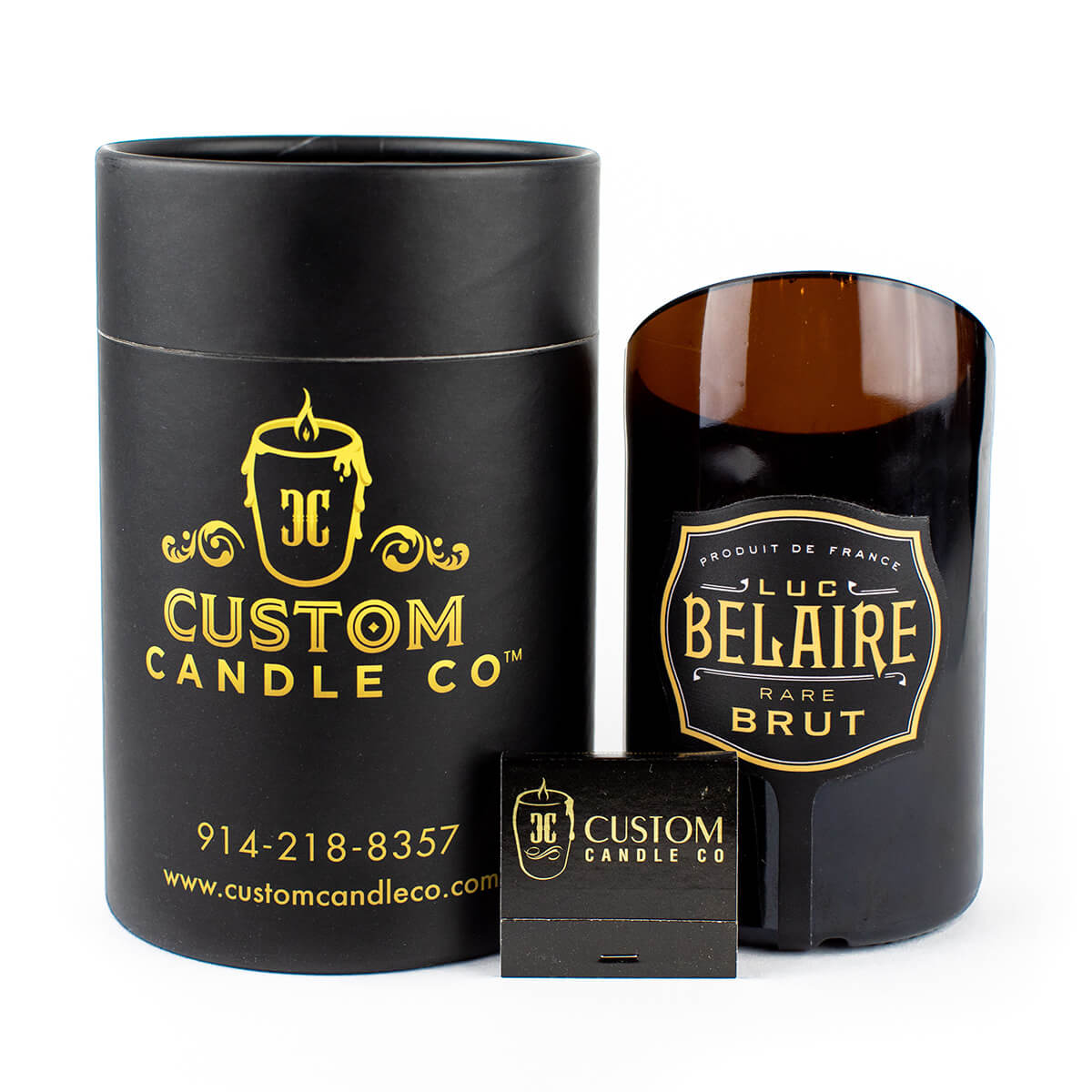 A black cylindrical custom candle container, a Recycled Champagne Candle – Luc Belaire Rare Brut, and a Custom Candle Co. matchbox are displayed against a white background.