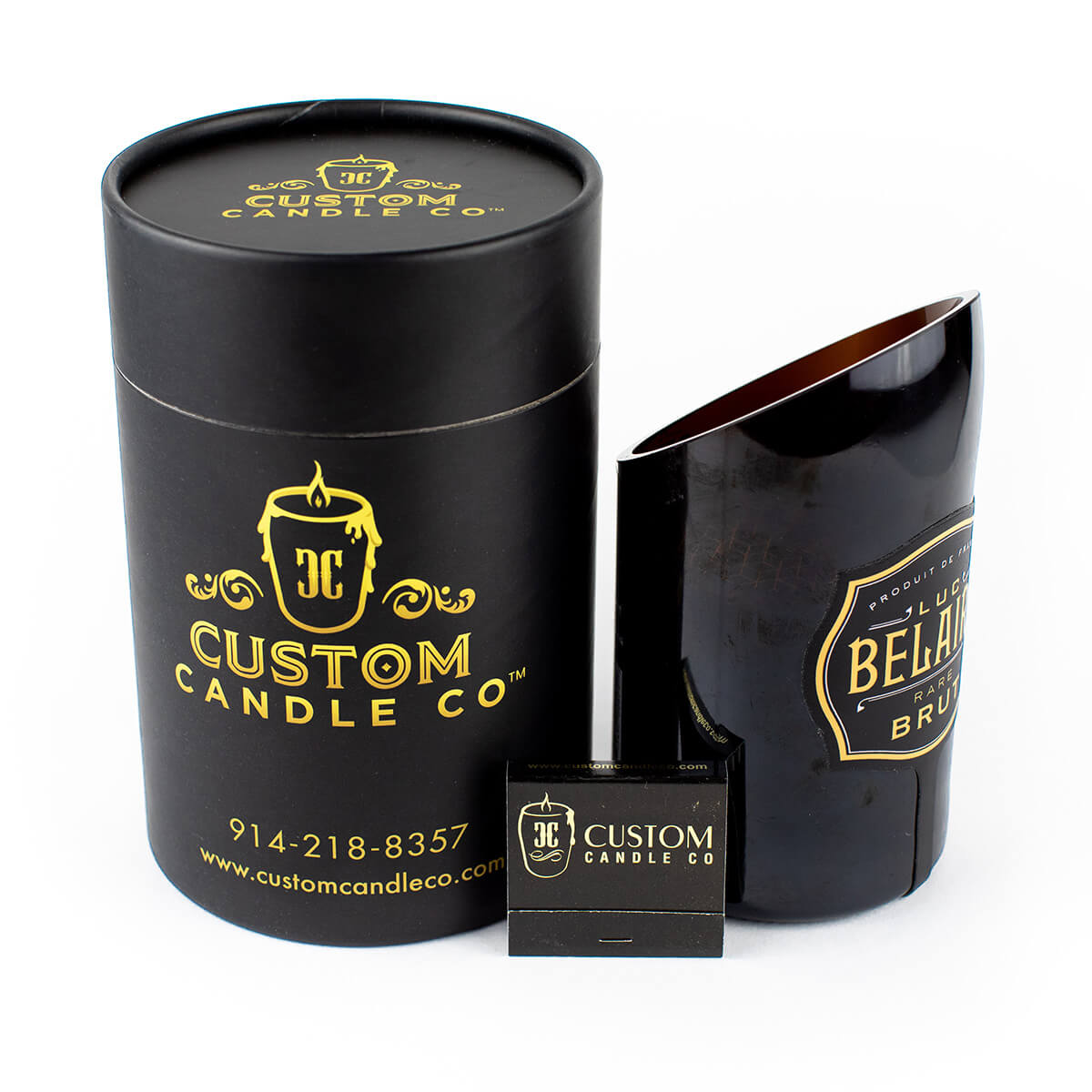 A recycled Luc Belaire Rare Brut champagne bottle candle, hand-poured soy wax, paired with a box of matches—both branded with "Custom Candle Co." and gold text.