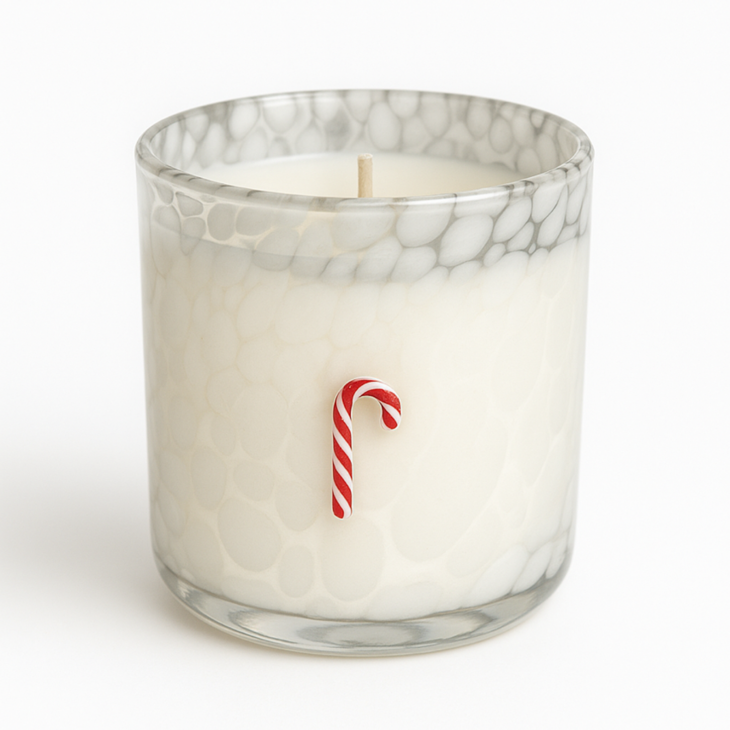 The Candy Cane Glass Candle features natural wax in a textured glass holder, adorned with a small red and white candy cane decoration for a festive touch.