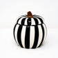 The Ceramic Large Black Line Pumpkin Candle, featuring black and white vertical stripes and a brown stem, adds festive charm and a striking accent to any space—perfect for seasonal décor or as a unique centerpiece.