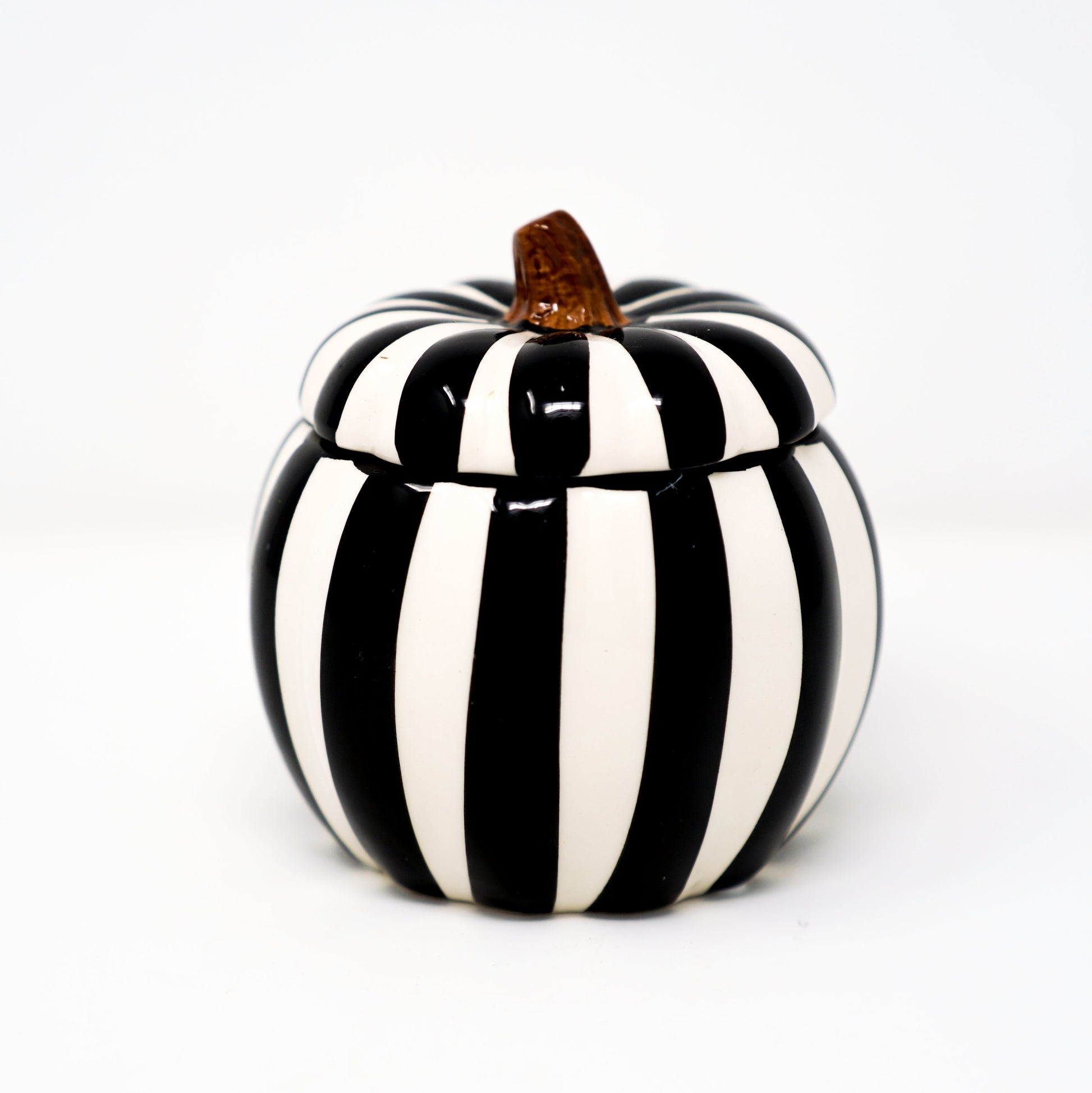 The Ceramic Large Black Line Pumpkin Candle, featuring black and white vertical stripes and a brown stem, adds festive charm and a striking accent to any space—perfect for seasonal décor or as a unique centerpiece.