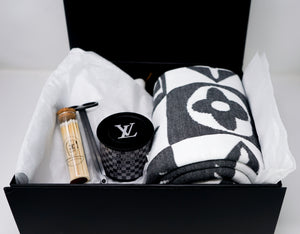 A black gift box features a cozy cotton throw, "LV" logo candle, metal tool, and glass tube with incense sticks—an elegant addition to Custom Design Baskets.