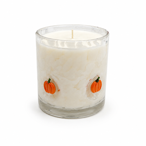 Halloween artisan candle with orange glass pumpkins on a cream vessel