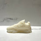 The Y500 – White Sneaker Candle – Small, shaped like a classic sneaker, sits on a white surface with a light gray marbled background. This hand-poured candle offers the refreshing black ice fragrance.