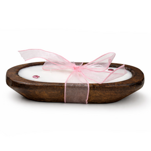 The Pink Ribbon - Dough Bowl Candle is a hand-poured soy candle in a wooden bowl, adorned with a pink ribbon and decorative beads, displayed on a white background.