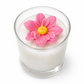 Candle in a glass jar with a pink flower on top against a white background