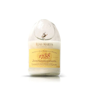 The Recycked 1738 Remy Martin Diagonal Cut Champagne Candle is a glass candle crafted from recycled bottles, featuring a yellow label and designed to resemble a Rémy Martin 1738 cognac bottle, displayed on a plain white background.