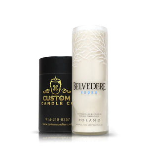 A Recycled Belvedere Vodka Candle sits beside a black "Custom Candle Co." container, showcasing an artisanal candle crafted from an upcycled vodka bottle.