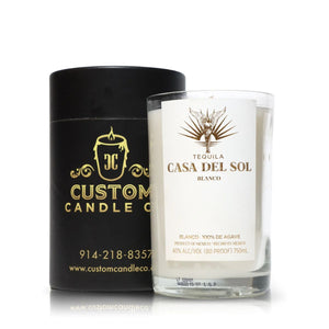A glass Recycled Blanco Tequila Candle is displayed beside a black cylindrical box featuring "Custom Candle Co." branding and contact information.