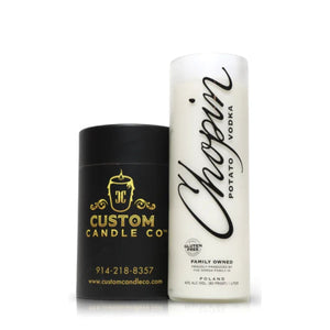 A white Recycled Chopin Potato Vodka Candle sits beside a black Custom Candle Co. container—a sleek display of artisanal craftsmanship for candle enthusiasts.