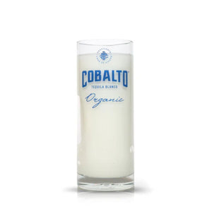 A Recycled Cobalto Tequila Blanco Candle, crafted from repurposed tequila bottles and featuring branded glass, is filled with creamy white wax and set against a plain white background.