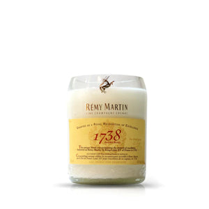 The Recycled Remy Martin Champagne Cognac Candle is a white candle in a glass container, featuring a Rémy Martin 1738 Accord Royal label on the front and beautifully crafted from recycled bottles.