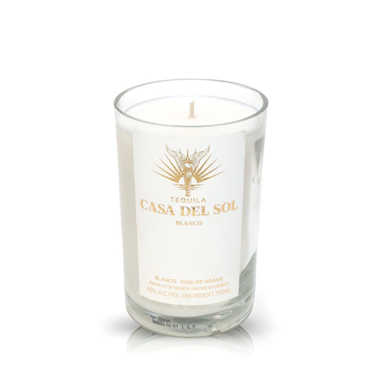 A clear glass Recycled Blanco Tequila Candle with a white wax fill features a gold logo and "Casa Del Sol Blanco" text, along with detailed product info printed on the front.