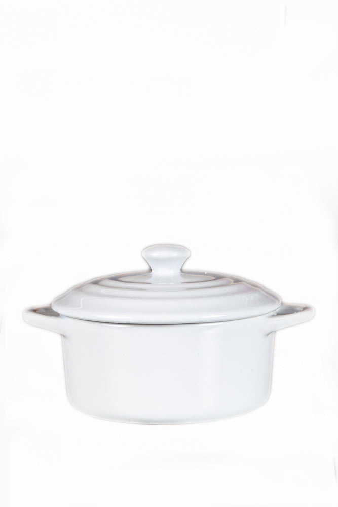 The White Mini Cereal Crockpot Candle is a white ceramic dish with handles and a lid, designed to resemble a stylish crockpot candle, shown against a plain white background.