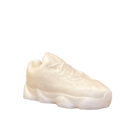 The Y500 – White Sneaker Candle – Small is a hand-poured, white candle shaped like a sneaker, featuring laces and textured details, shown on a plain white background.